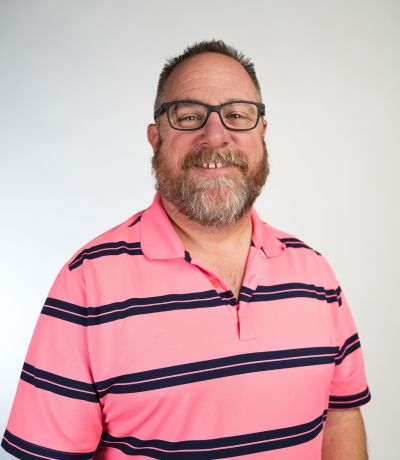 Jason Robinson A smiling man with a beard and glasses, wearing a pink polo shirt with dark blue horizontal stripes, identified as Jason Robinson, Warehouse Inventory Manager. His favorite product is Almond Joy Sno