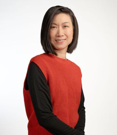 Feibi Habbinga A smiling person with short, dark hair, wearing a reddish-orange sweater vest over a black long-sleeved shirt, identified as Feibi Habbinga, Creative Production Manager. Their favorite product is Strawberry Sno.