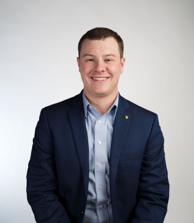 Jefferson Berridge A smiling man with short brown hair, wearing a dark blue suit jacket and a light blue collared shirt, identified as Jefferson Berridge, Production Specialist. His favorite product is Shark Attack Sno.