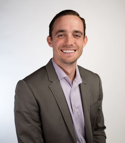 Zyler Buchanan A smiling man with short, dark hair wears a gray suit jacket over a light purple collared shirt, identified as Zyler Buchanan, Business Development Manager. His favorite product is Strawberry Sno.