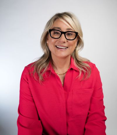 Trena Sutton A smiling woman with blonde hair and black-framed glasses wears a bright red collared shirt and a gold chain necklace, identified as Trena Sutton, Internal Operations Specialist. Her favorite product is OREO® Cookie Smoothie.