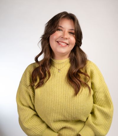 Alexa Swart A smiling person with long, wavy brown hair and a lip piercing wears a light green knitted sweater, identified as Alexia Swart, Finance Intern. Their favorite product is Strawberry Freezecake Sno.