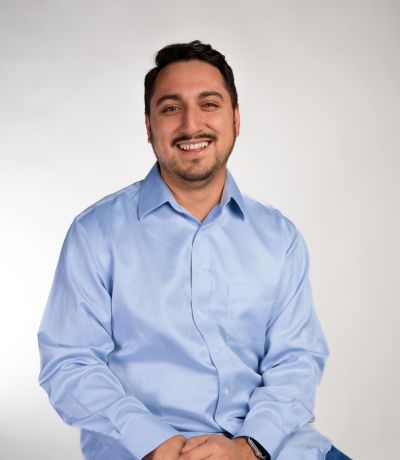 John Smith A smiling man with short dark hair and a mustache and beard wears a light blue button-up shirt, identified as John Smith, Financial Specialist. His favorite product is Cherry Sno with Sour Patch® Sauce.