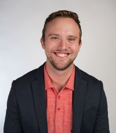 Christopher Kostedt A smiling man with short brown hair and a beard, wearing a dark blue blazer over a coral polo shirt, identified as Christopher Kostedt, Floor Supervisor. His favorite product is Bomb Pop® Jr. Signature Sno.