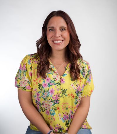 Cierra Miller A smiling woman with long, dark, wavy hair wears a yellow floral print blouse, identified as Cierra Miller, Director of Field Operations. Her favorite product is OREO® Cookie Signature Sno with OREO extreme toppings.