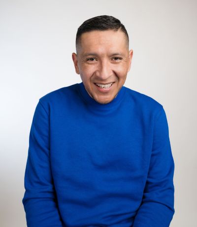 Jaime Chavarria A smiling person with short dark hair, wearing a bright blue turtleneck sweater, identified as Jaime Chavarria, Warehouse Packing Specialist. Their favorite product is Wavebender Smoothie.